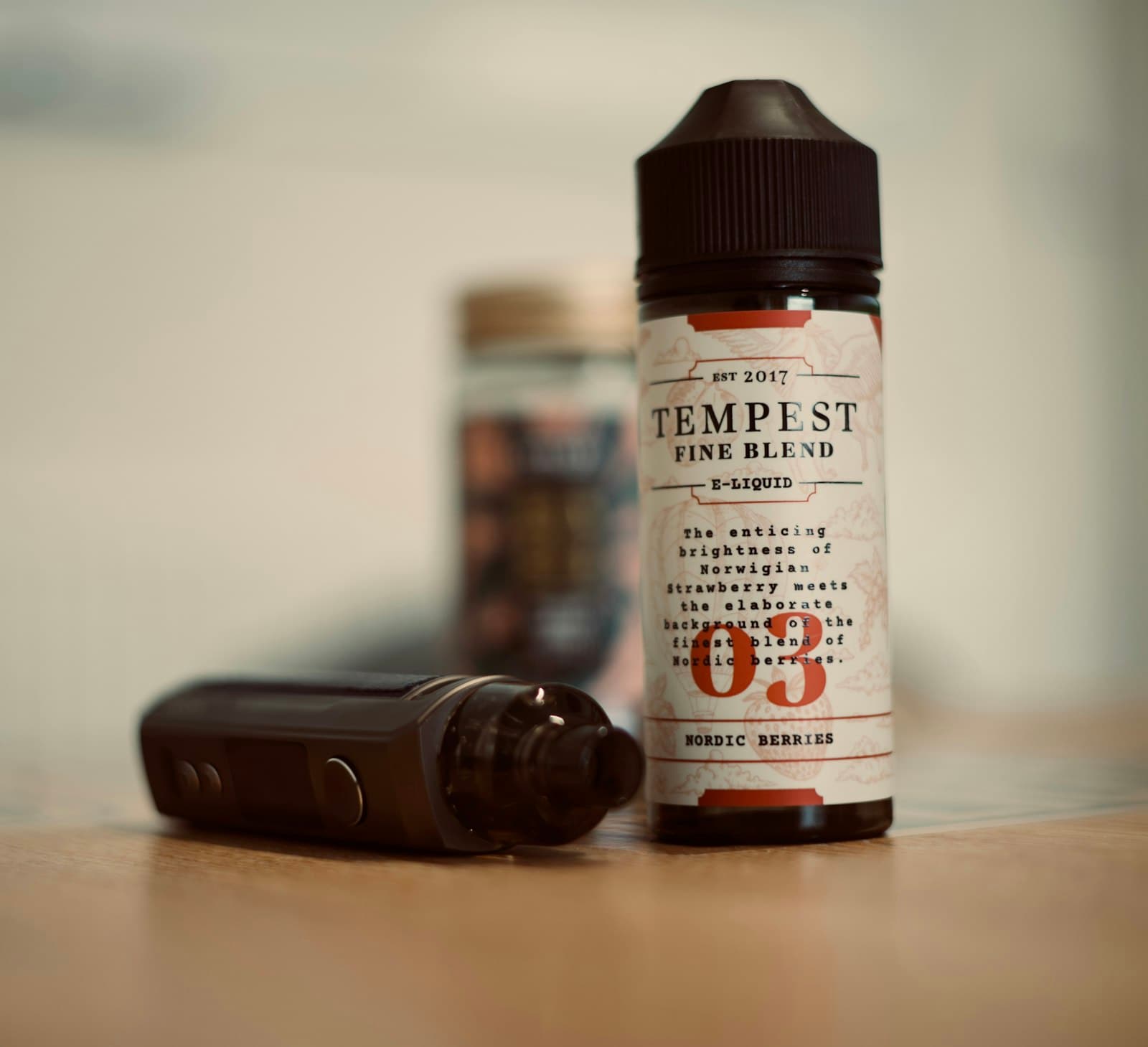 A pod vape kit standing next to a bottle of e-liquid on a wooden surface