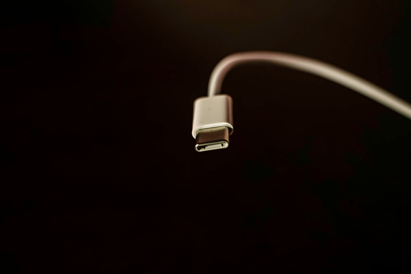 Close-up of a white USB-C charging cable and connector against a dark background