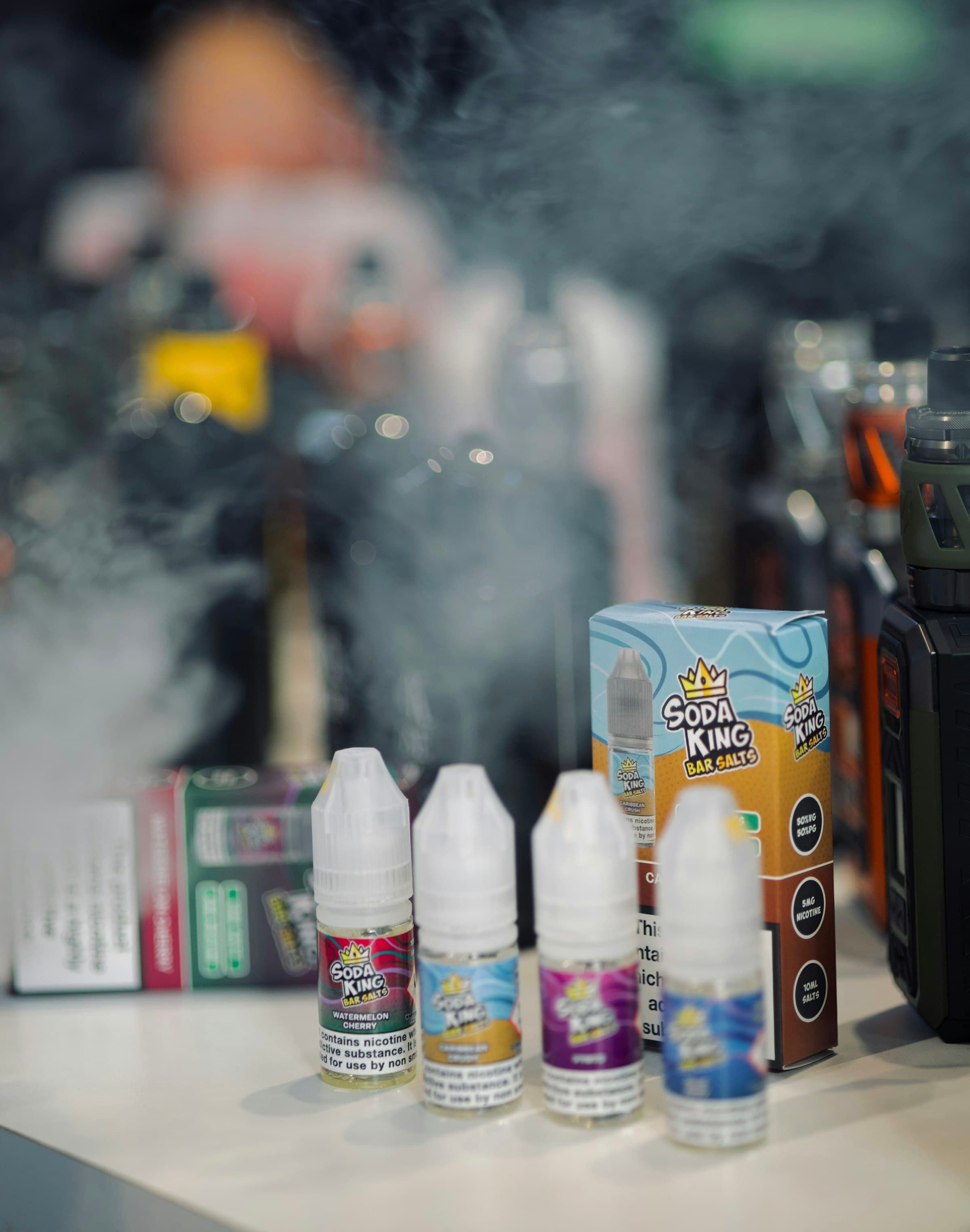 Several small 10ml nicotine salt e-liquid bottles lined up on a shop counter, each labelled with its flavour and nicotine strength